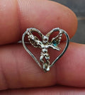 Silver-tone angel pin in heart shape with detailed wings, close-up on fingertip