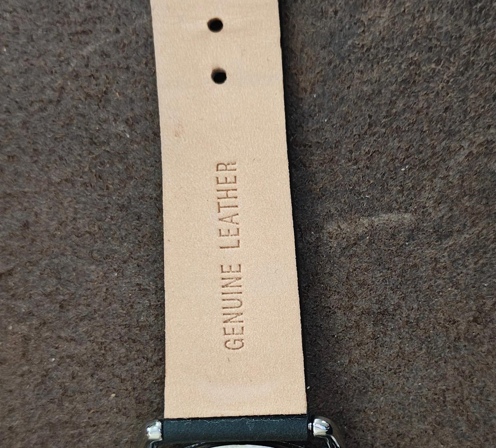 Men's leather strap detail with embossed "GENUINE LEATHER" text and buckle