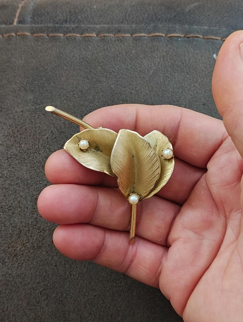 Gold textured leaf brooch close-up with faux pearl details on a thin pin