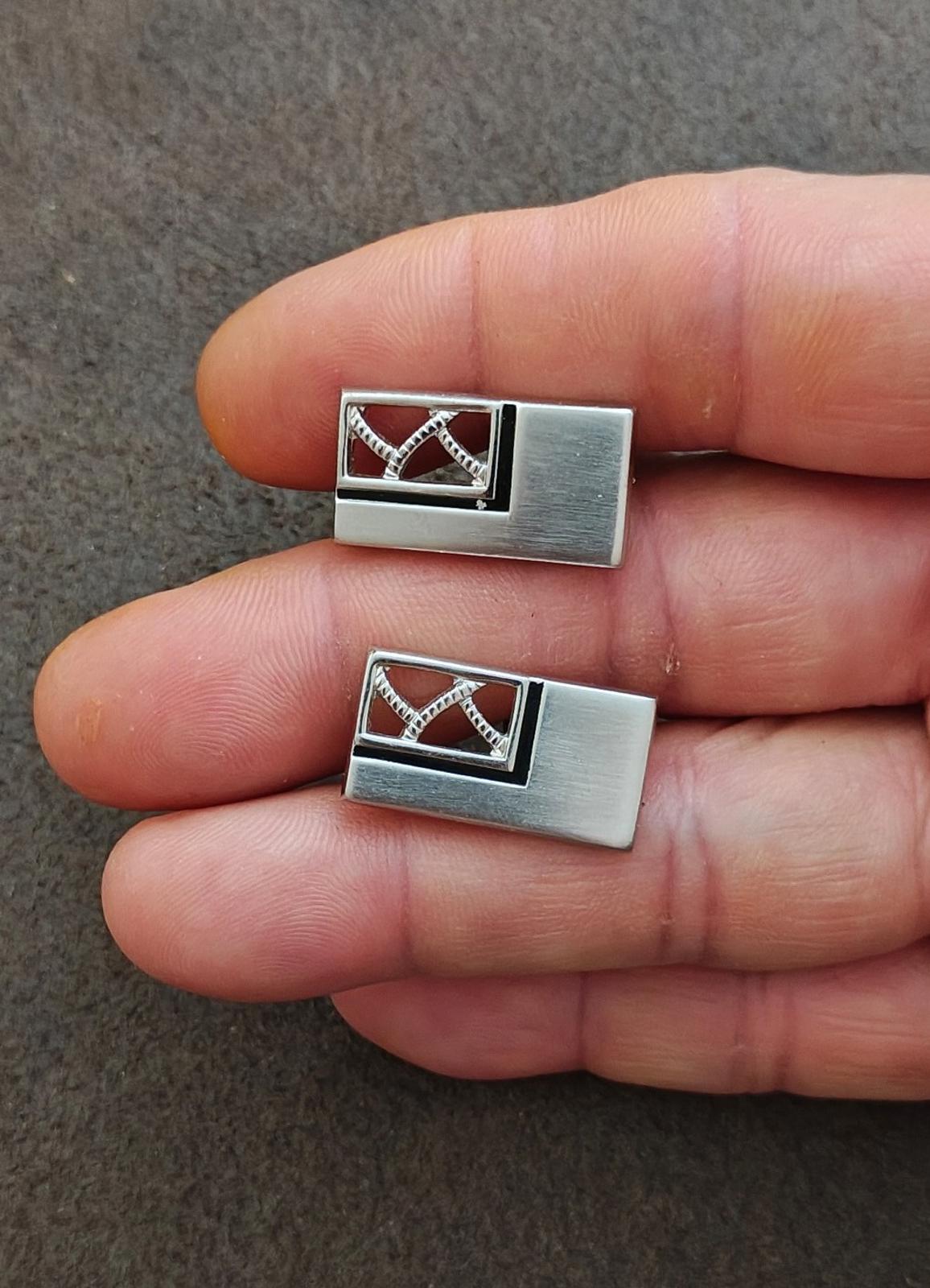 Pair of silver-tone cufflinks in hand, dark enamel front with crosshatch motif