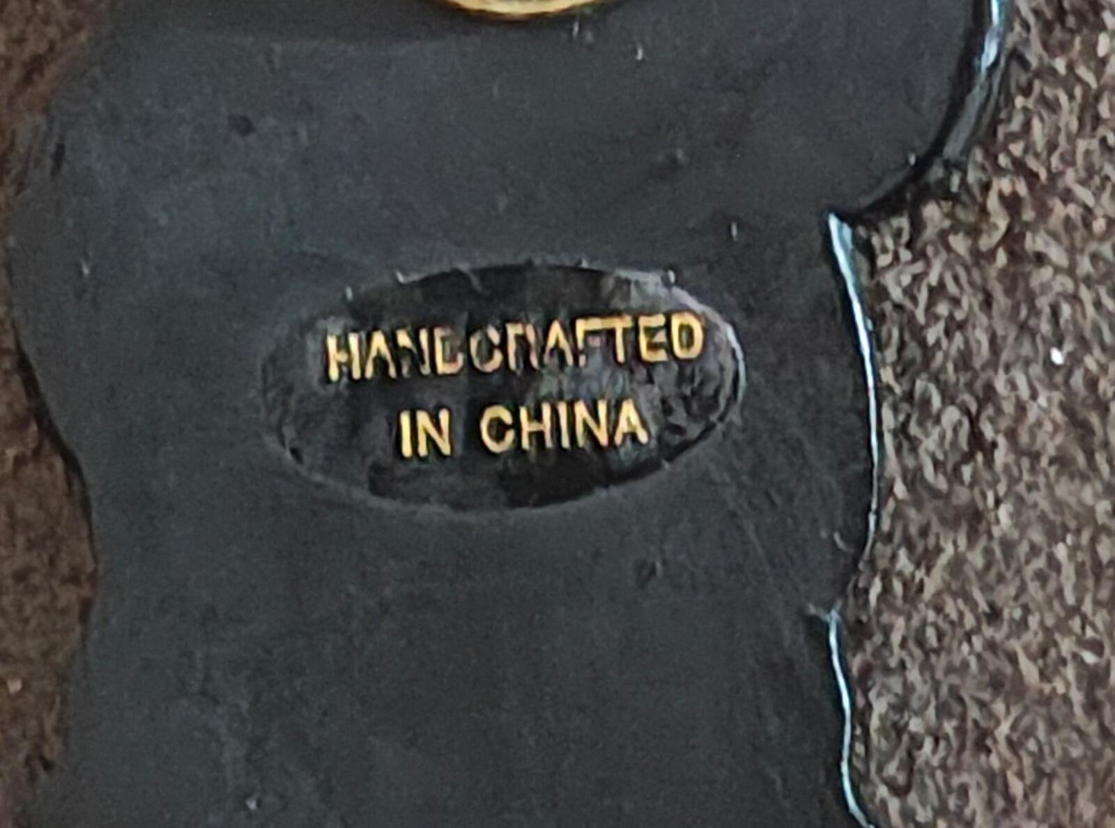 Black bear pin back stamp reading "HANDCRAFTED IN CHINA" in gold letters