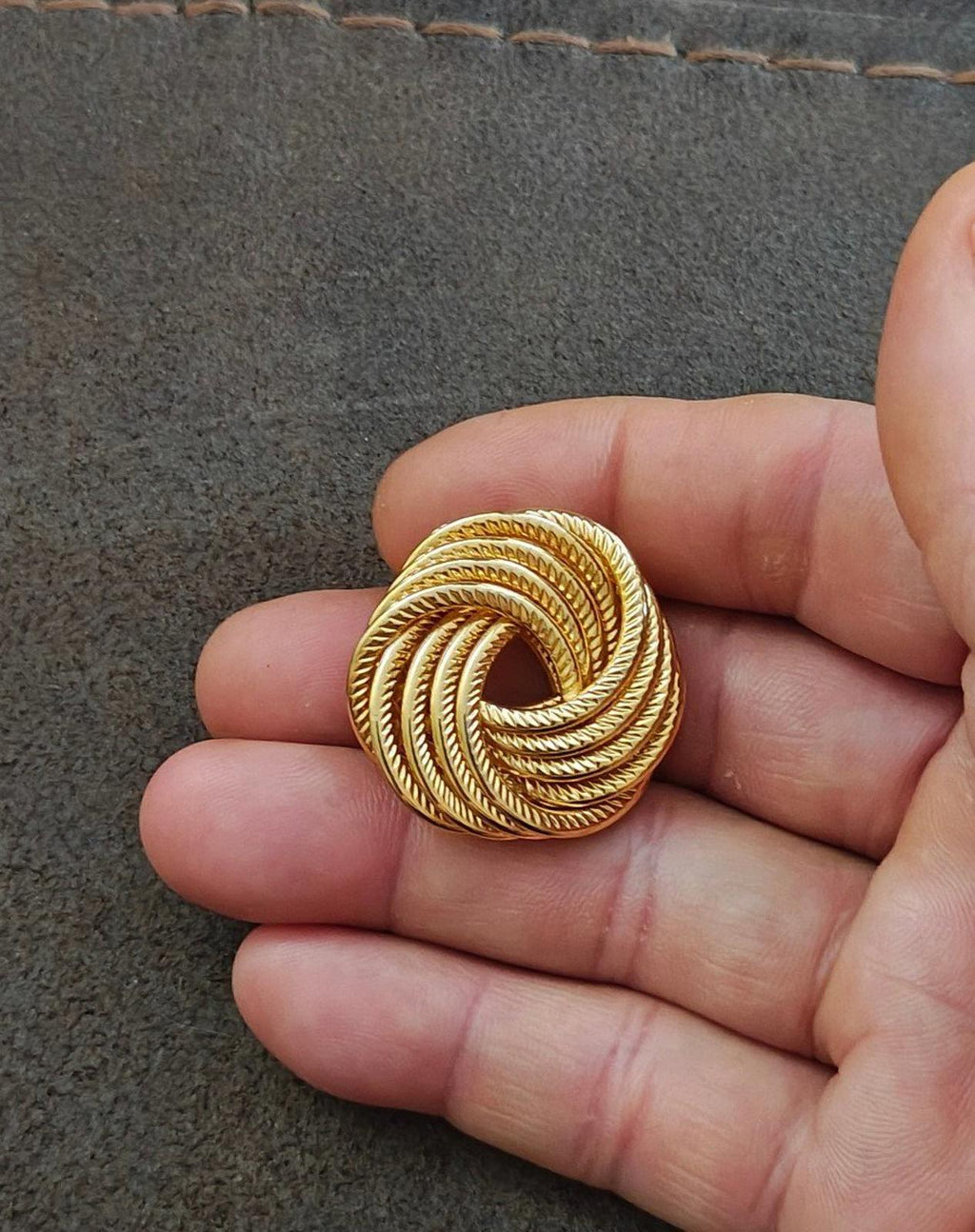 Gold tone spiral rope brooch pin held in hand, circular swirl detail
