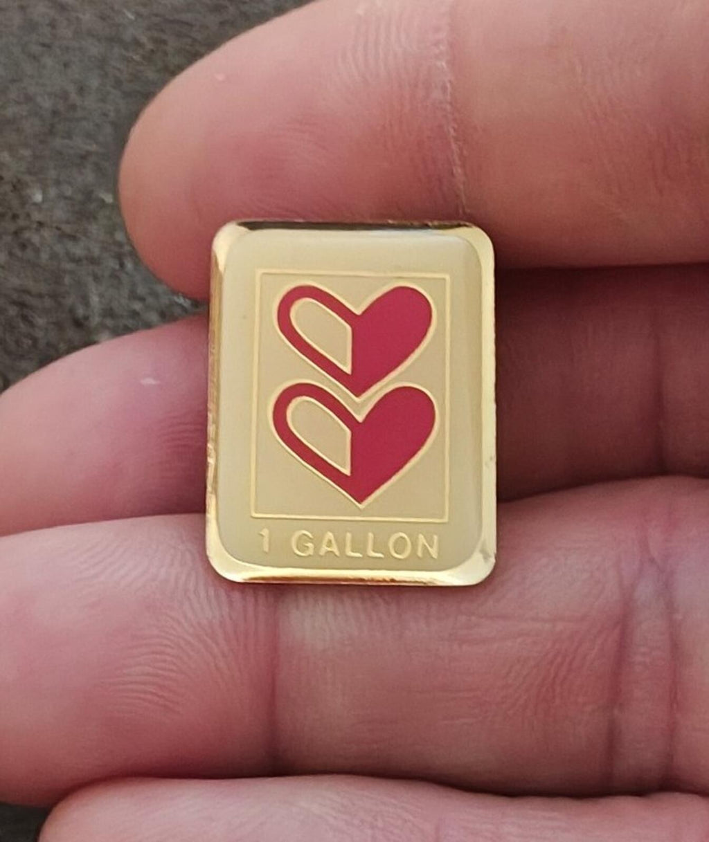 Gold-tone enamel pin with two red hearts and '1 GALLON' text