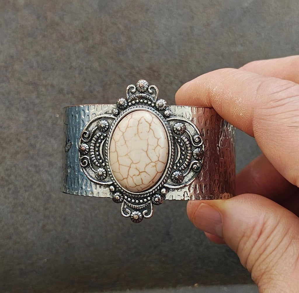 Silver hammered cuff bracelet with oval beige stone and detailed filigree border, close view
