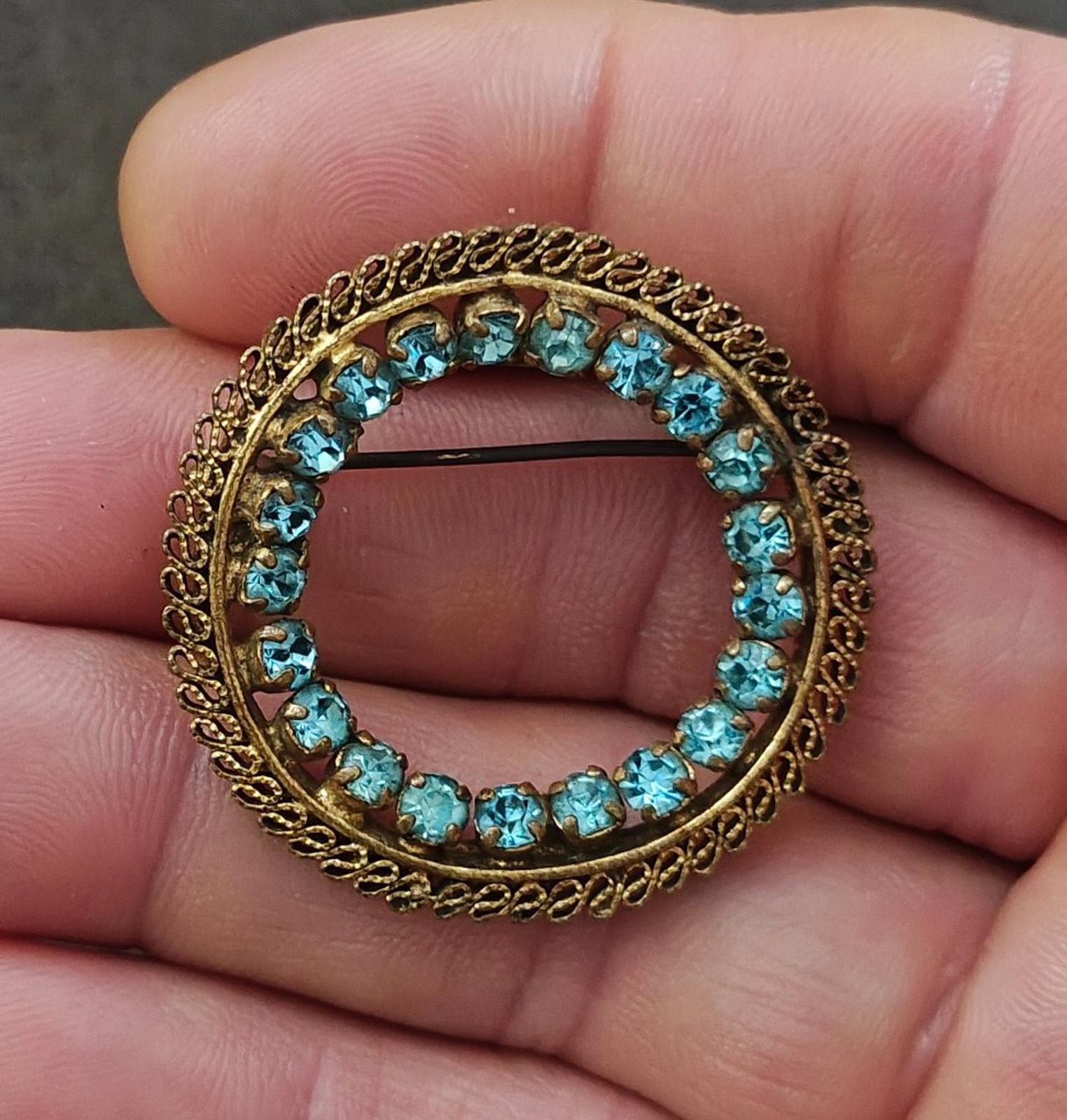 Gold-tone round brooch with blue filigree stones in a wreath frame