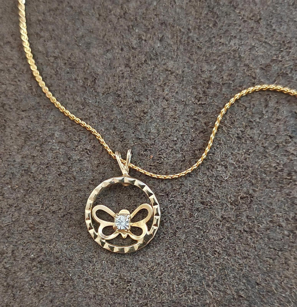 Gold-tone round pendant necklace featuring bow butterfly cutout and clear rhinestone