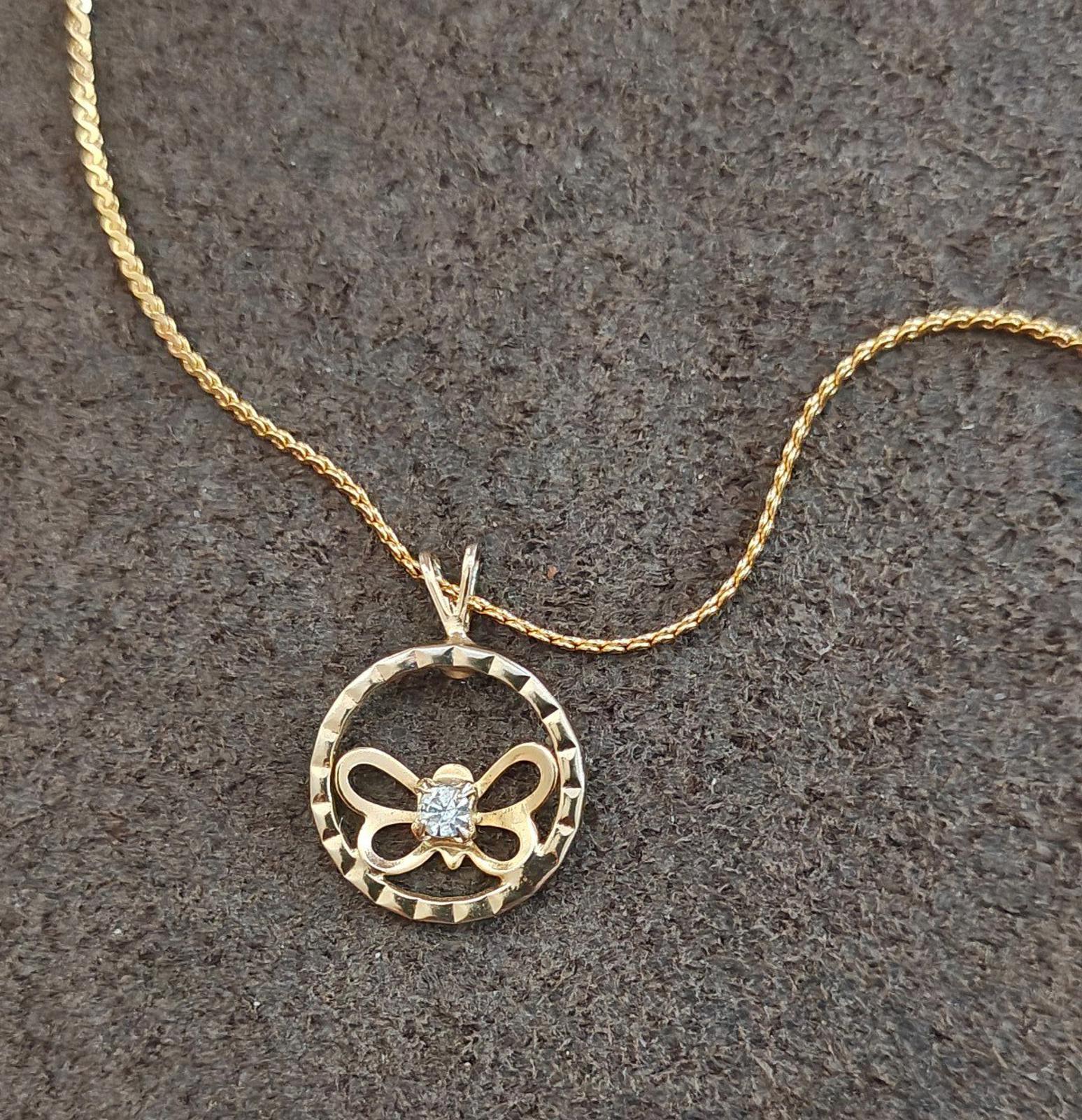 Gold-tone round pendant necklace featuring bow butterfly cutout and clear rhinestone