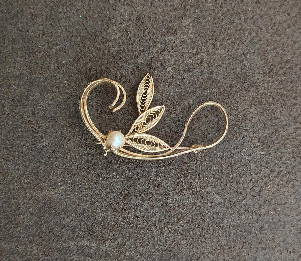 Gold tone leaf filigree brooch with faux pearl bead, leaf cluster and sweeping curves