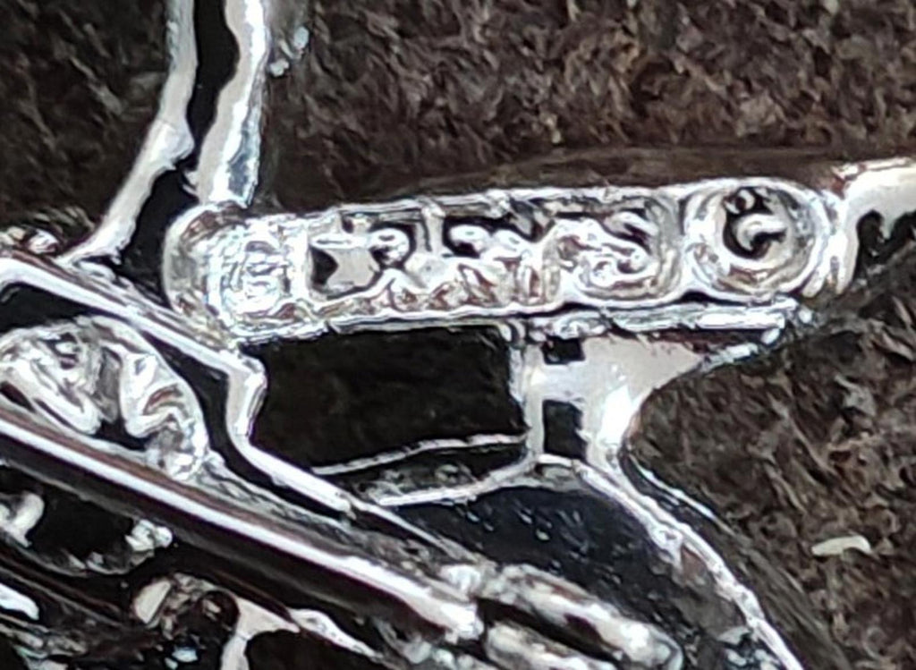 Close-up of silver-tone bow brooch pin back bar with engraved texture and hinge.
