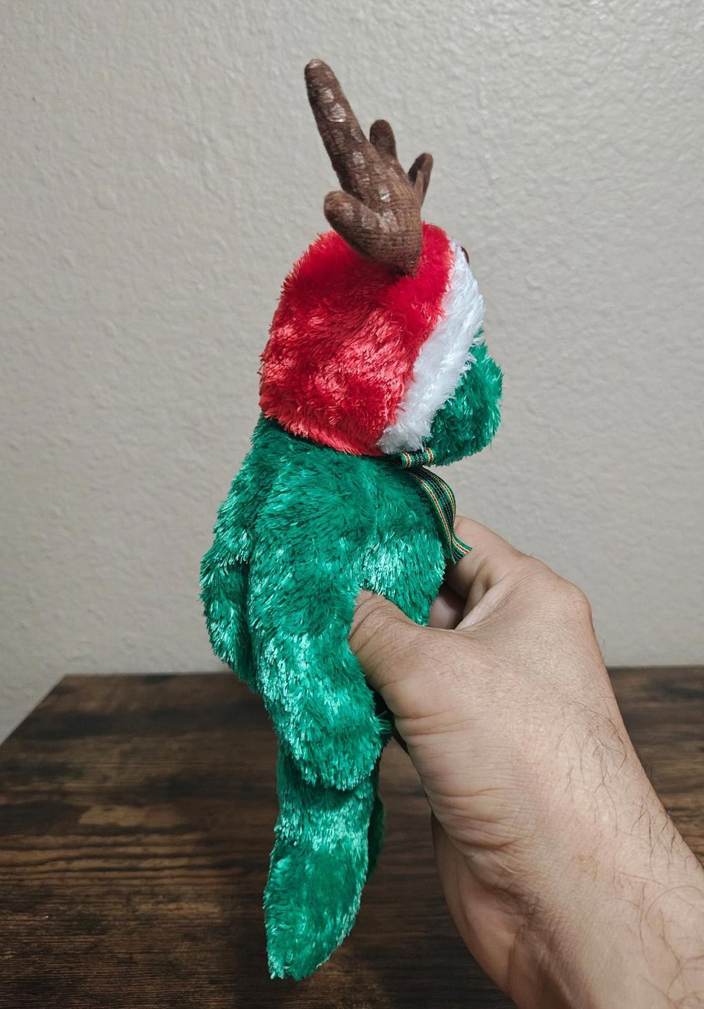 Green plush reindeer teddy bear with red cap, white trim, and antlers