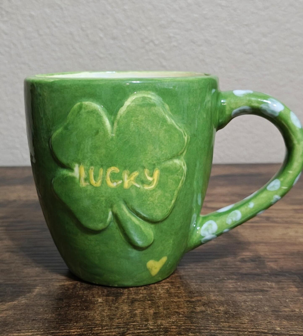 Green ceramic mug with clover-heart pattern and “Lucky” text, front view