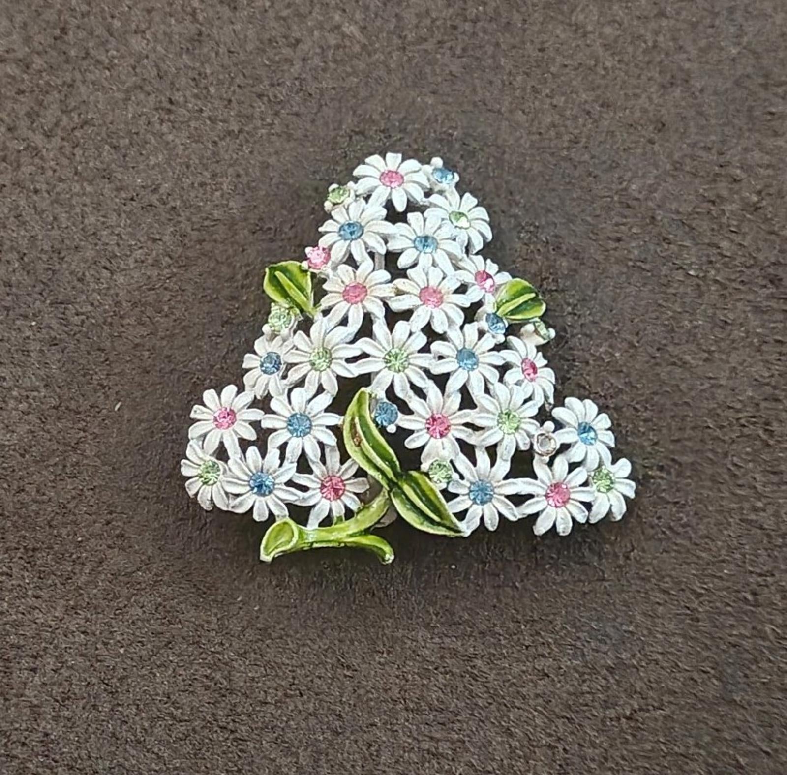 Gold-tone floral rhinestone brooch showing layered white blossoms with pink, blue, and green accents