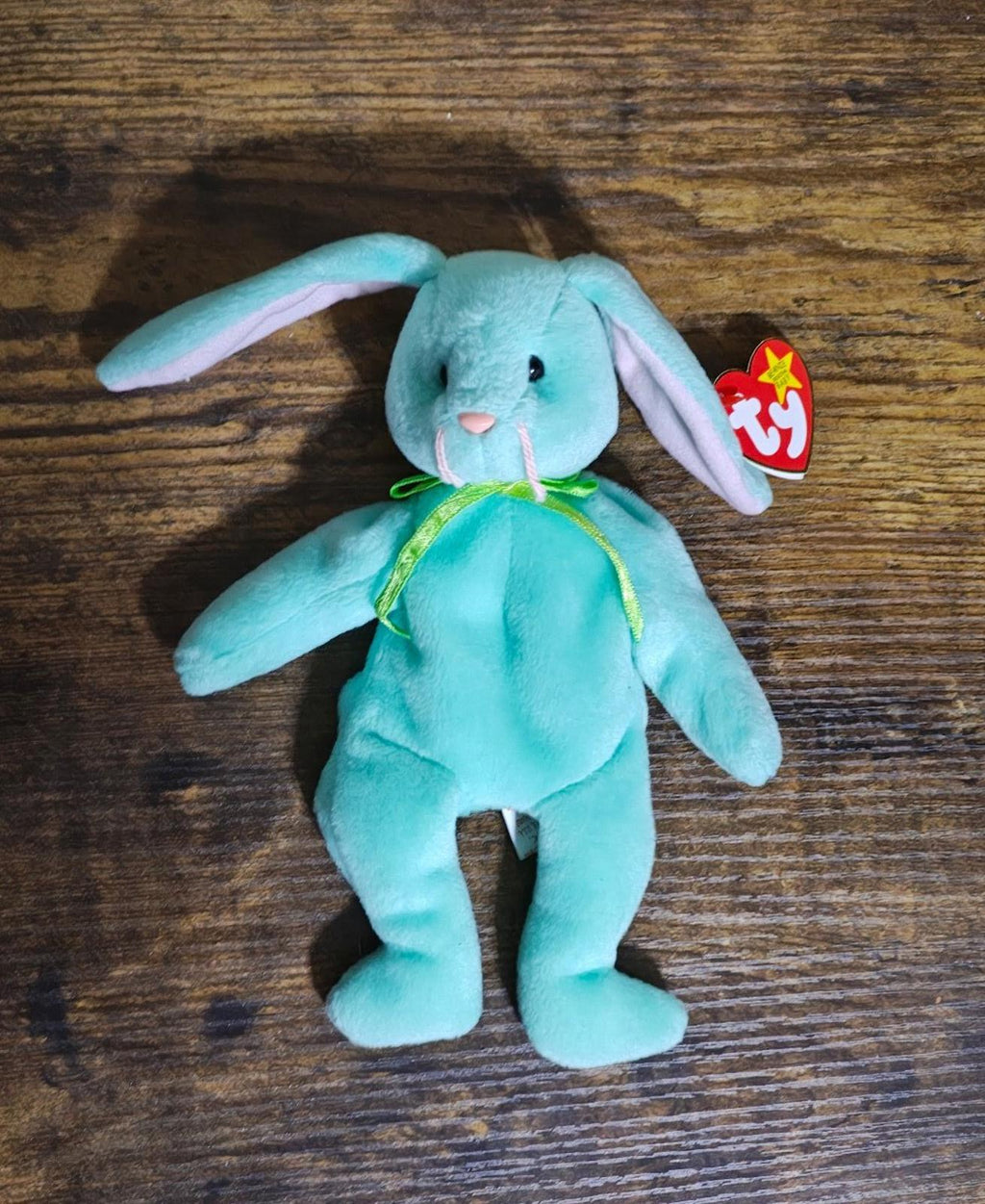 Teal plush bunny beanbag standing on wooden surface with Ty swing tag