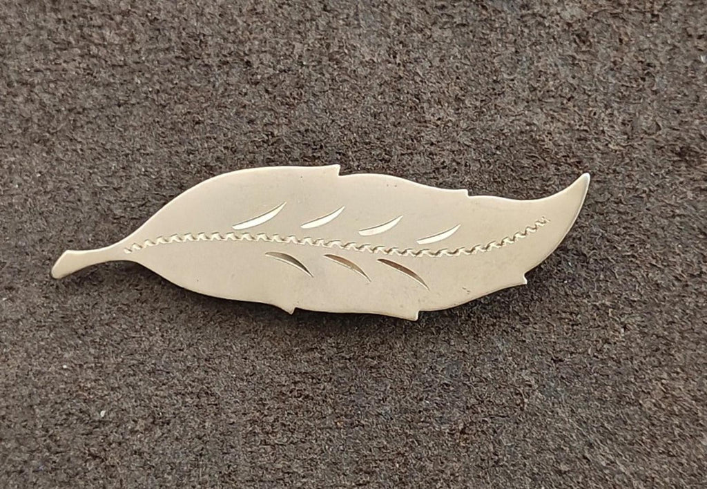 Gold leaf brooch with engraved leaf lines and textured border