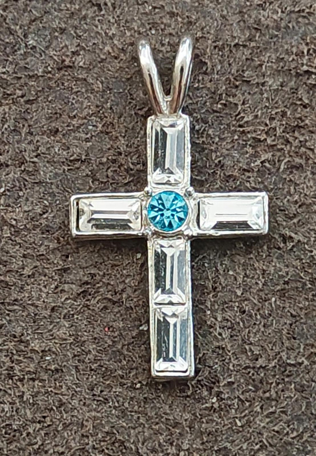 Silver tone rhinestone cross pendant with blue round center and clear baguette accents.