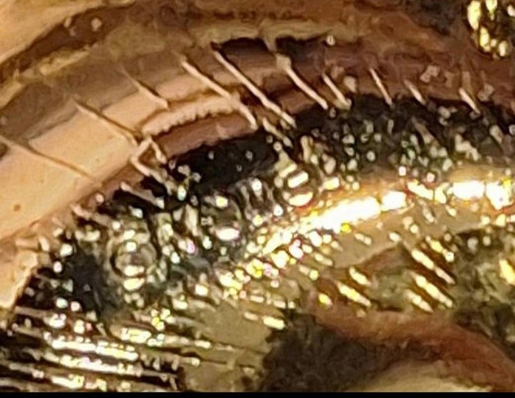 Close-up of gold heart pin surface with reflective detail and open cutout