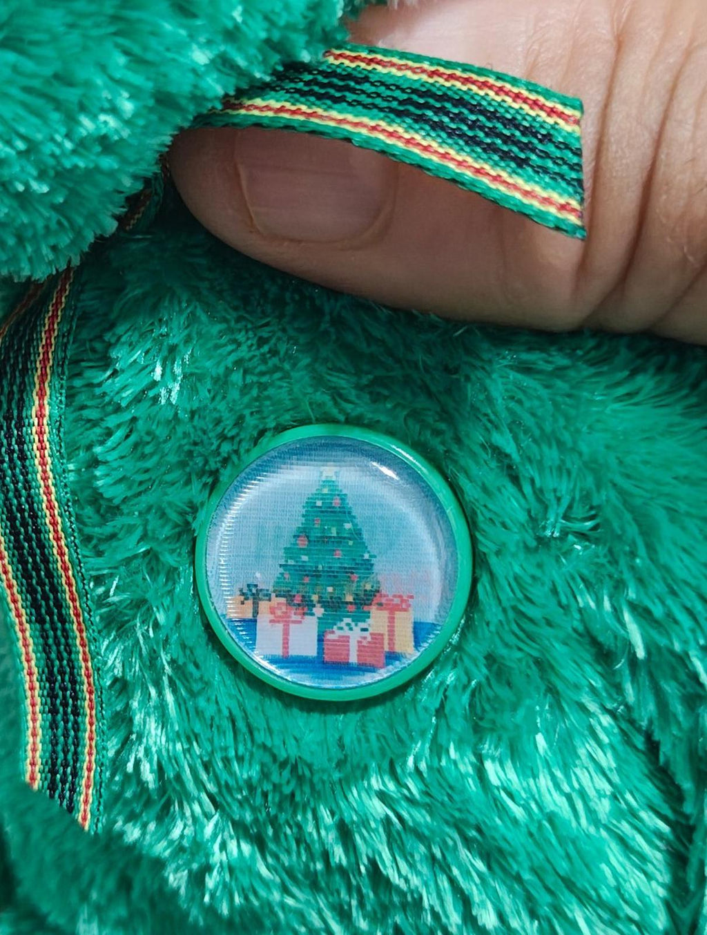 Close-up of green plush chest with plaid ribbon and round TY charm pin