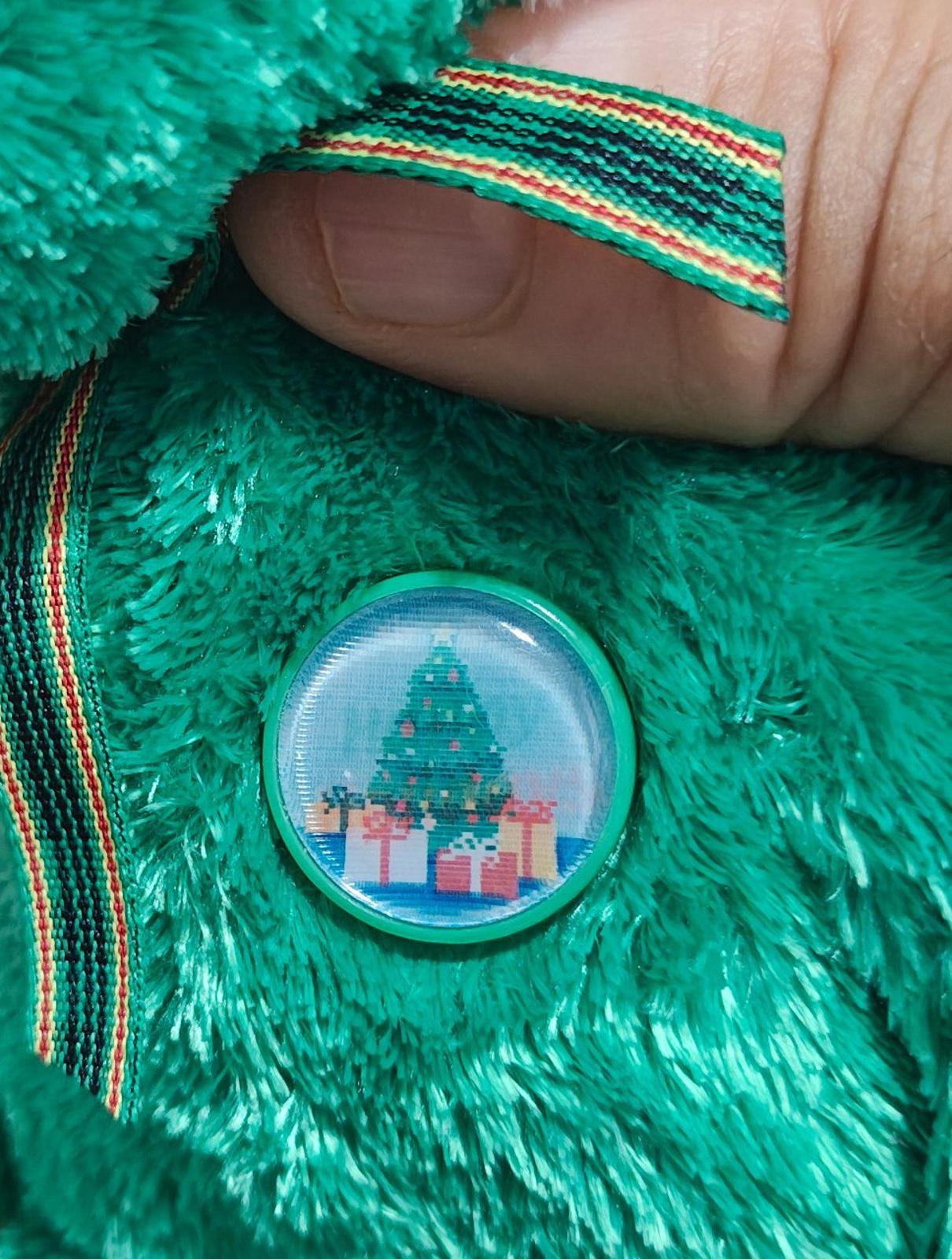 Close-up of green plush chest with plaid ribbon and round TY charm pin