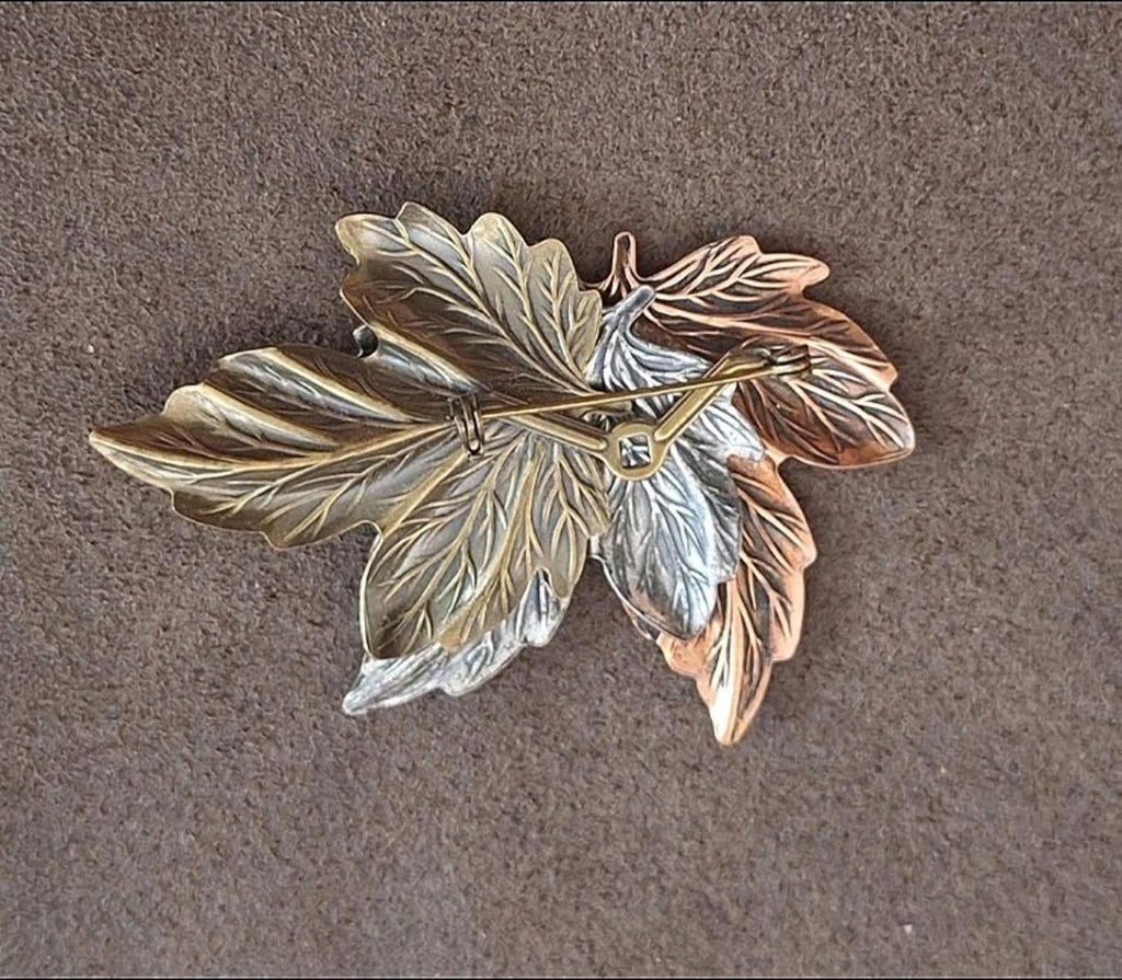 Layered leaf pin brooch with gold, silver, and brown leaves, angled view
