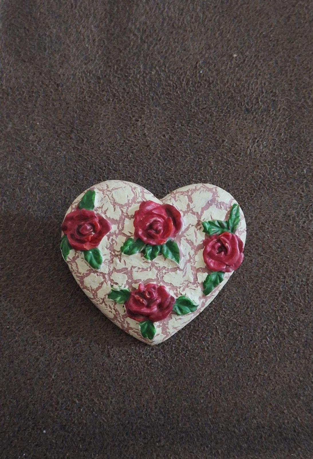 Heart-shaped resin pin with crackled white surface, scattered red roses and green leaves