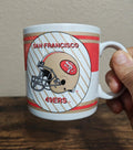 San Francisco 49ers helmet logo mug with red-and-white stripes and handle.