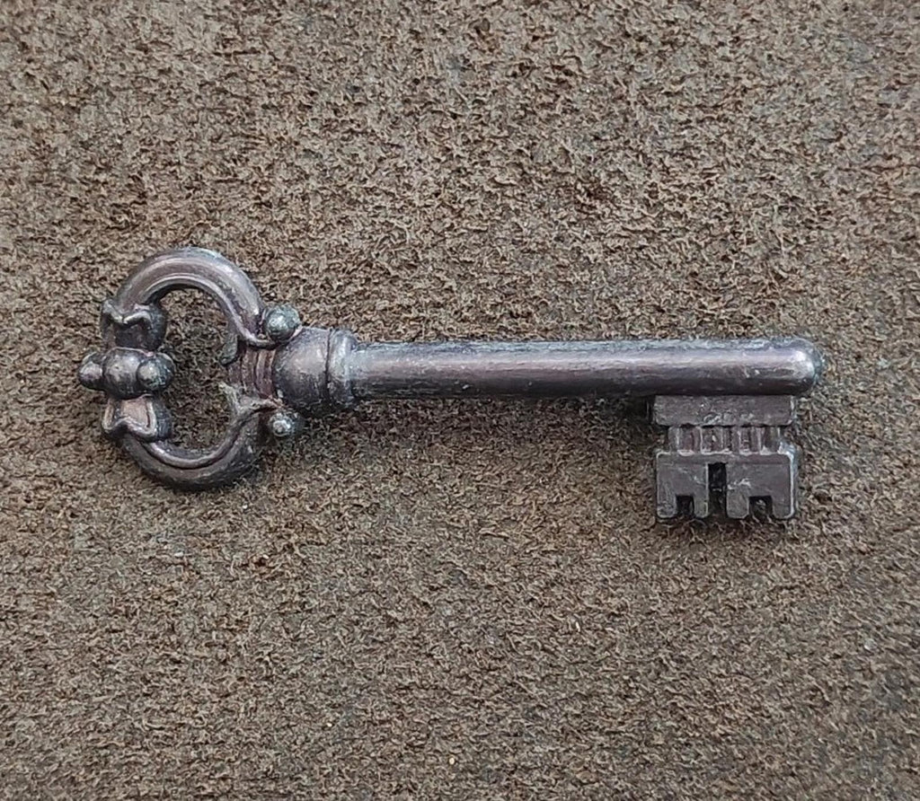 Pewter skeleton key brooch side view, ornate bow with textured shaft and teeth