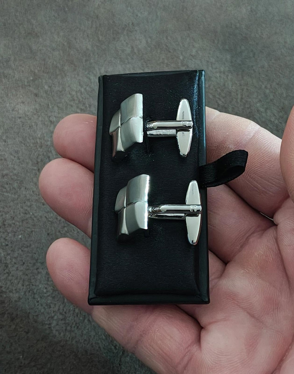 Front view of brushed silver square cuff links with hinged bars on black card