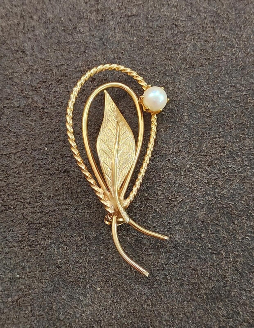 Gold tone leaf brooch featuring faux pearl and twisted rope oval border