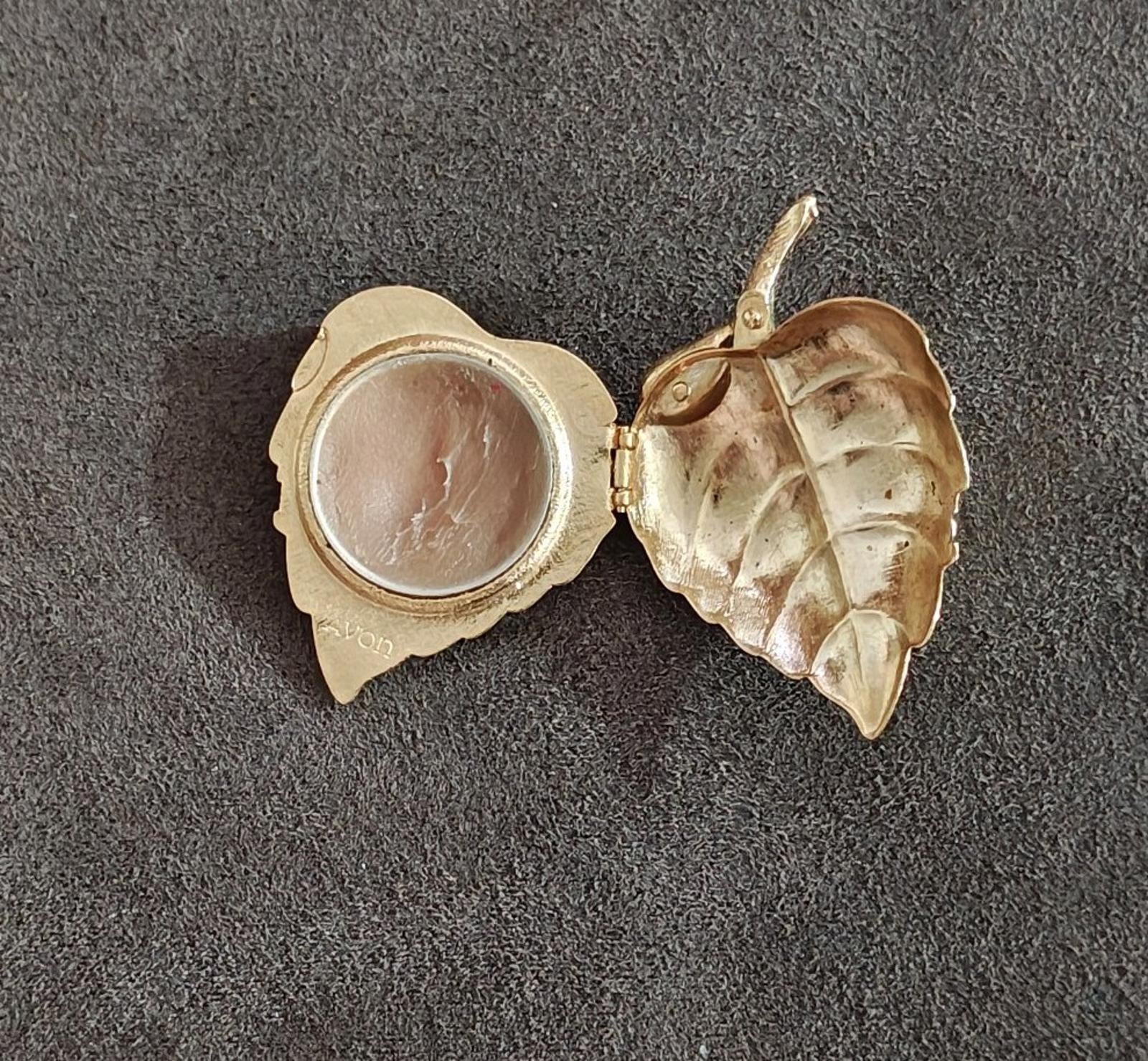 Gold tone leaf locket brooch open, showing interior circular photo compartment