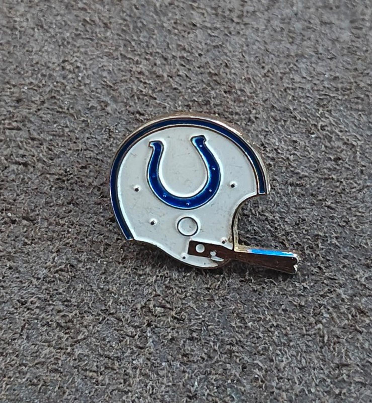 Gold-tone enamel tie clip with a white helmet and blue horseshoe emblem
