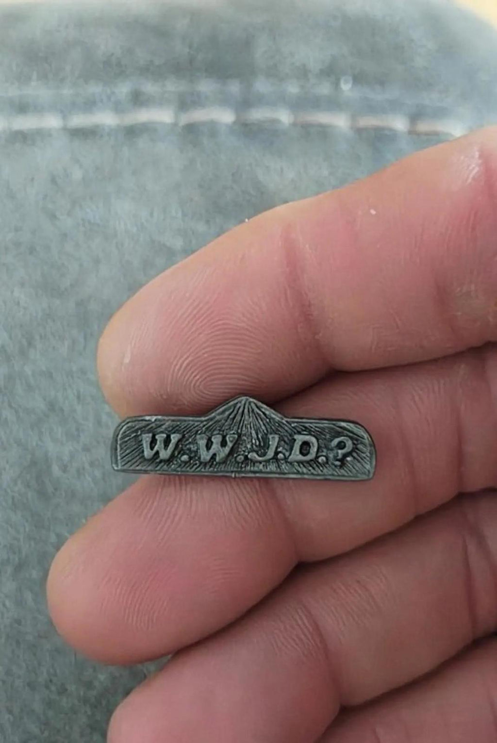 Pewter WWJD bar religious pin held in hand, stamped lettering visible