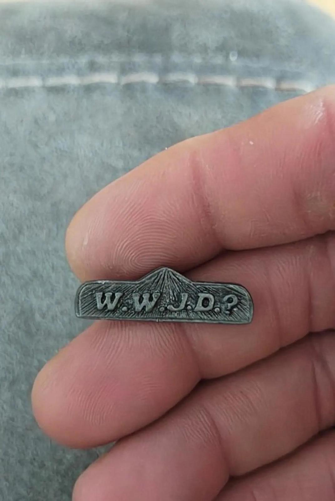 Pewter WWJD bar religious pin held in hand, stamped lettering visible