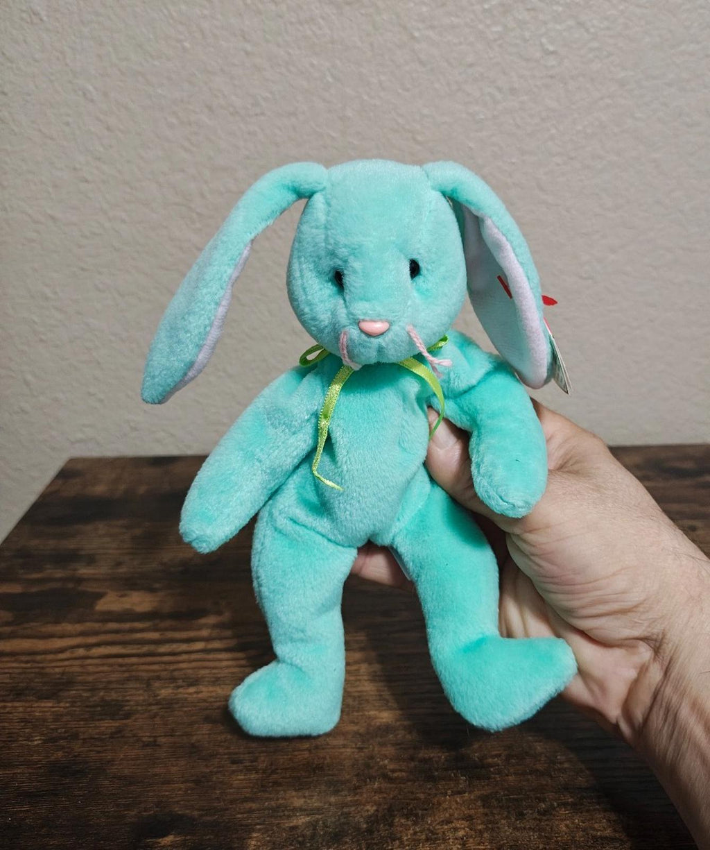 Teal plush bunny beanbag with long ears and stitched smile, held in hand