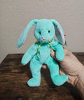 Teal plush bunny beanbag with long ears and stitched smile, held in hand