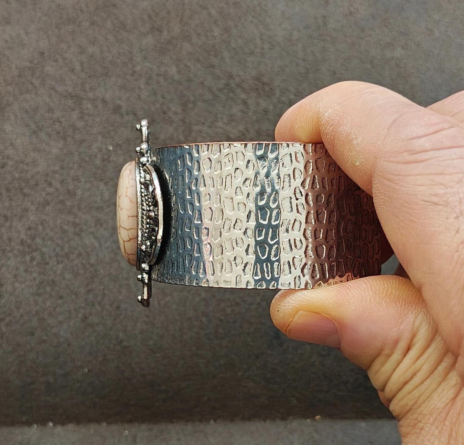 Silver hammered cuff bracelet side view with textured finish and oval stone setting, profile