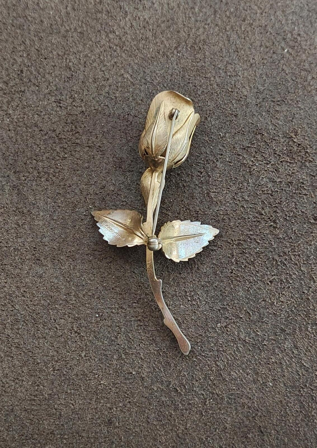 Gold tone rose brooch with light petals and pearl-like center detail, flat view