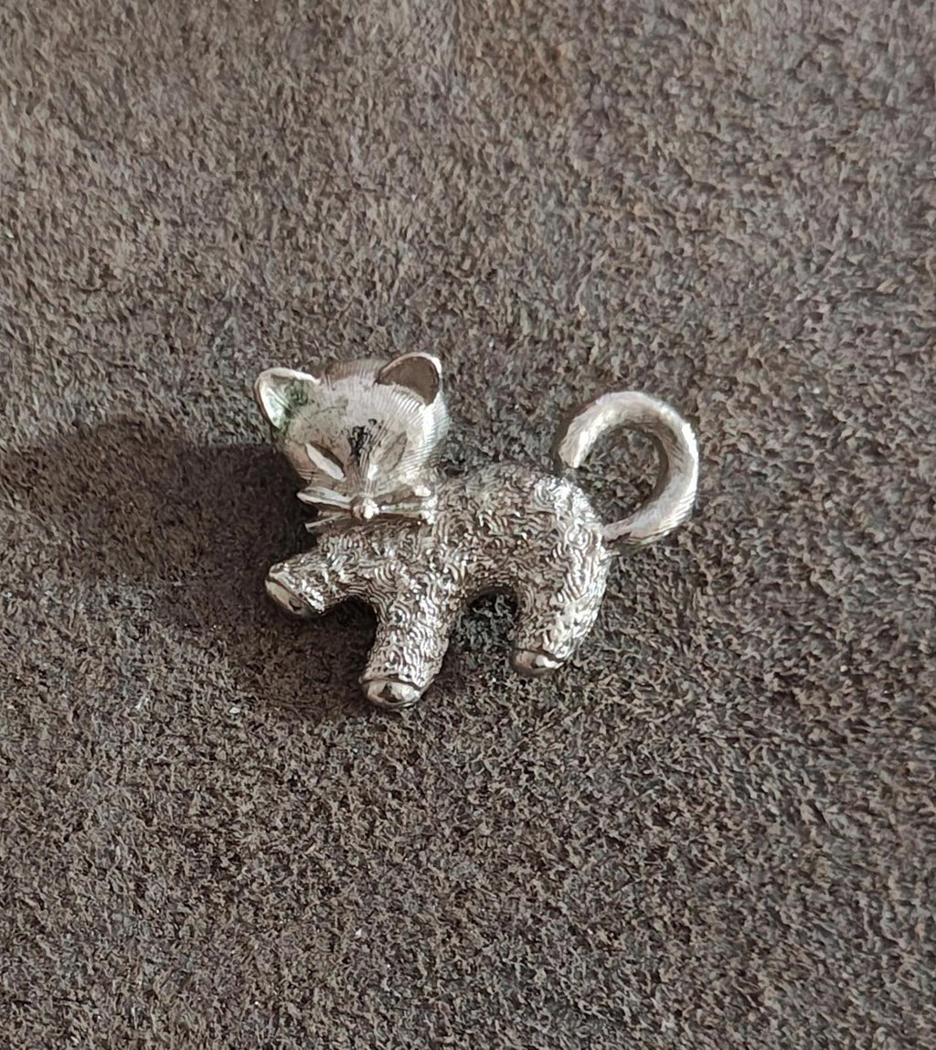 Silver-tone textured cat brooch pin with bow and raised ears.