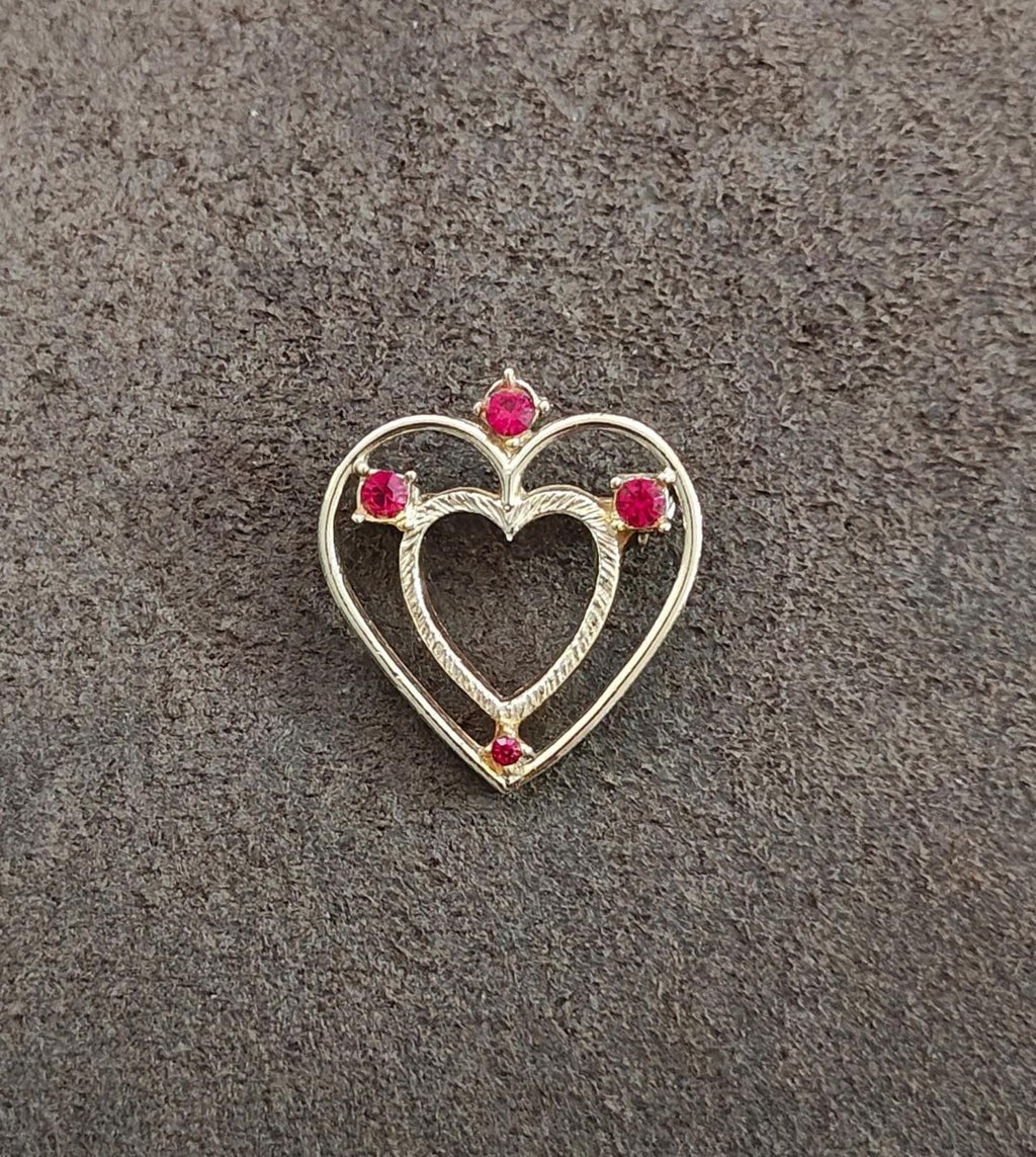 Small gold-tone heart brooch pin with red rhinestones, centered on surface