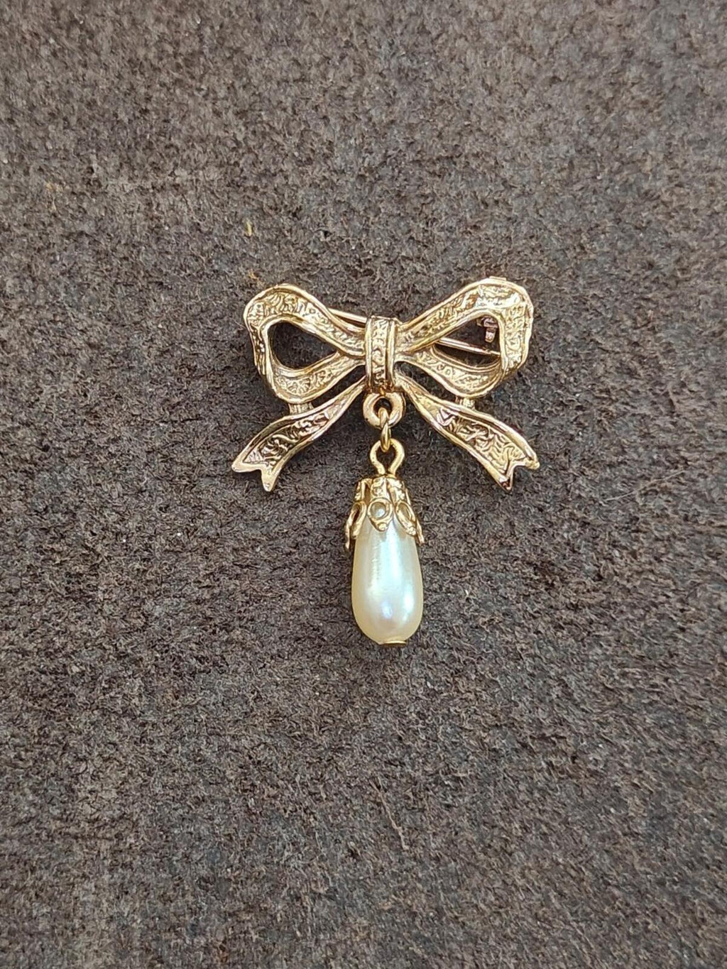 Gold bow brooch with hanging faux teardrop pearl drop, detailed embossed ribbon