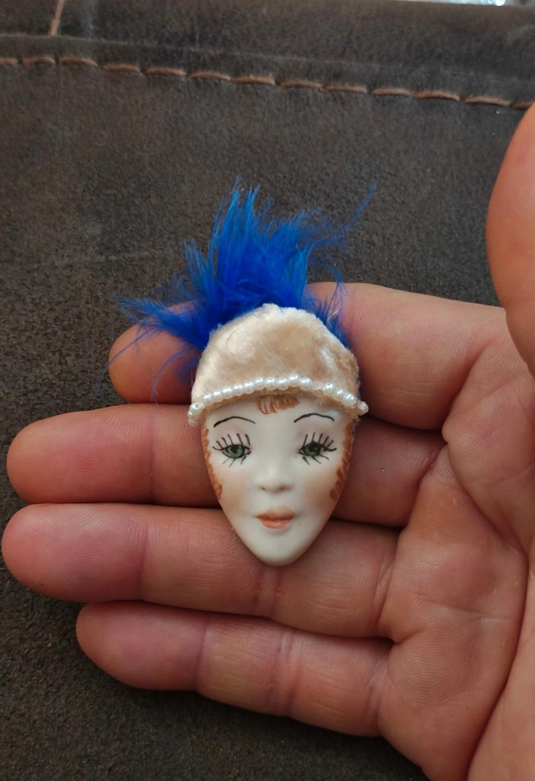 Doll face pin brooch with blue feather plume and cream pearl-trim headband