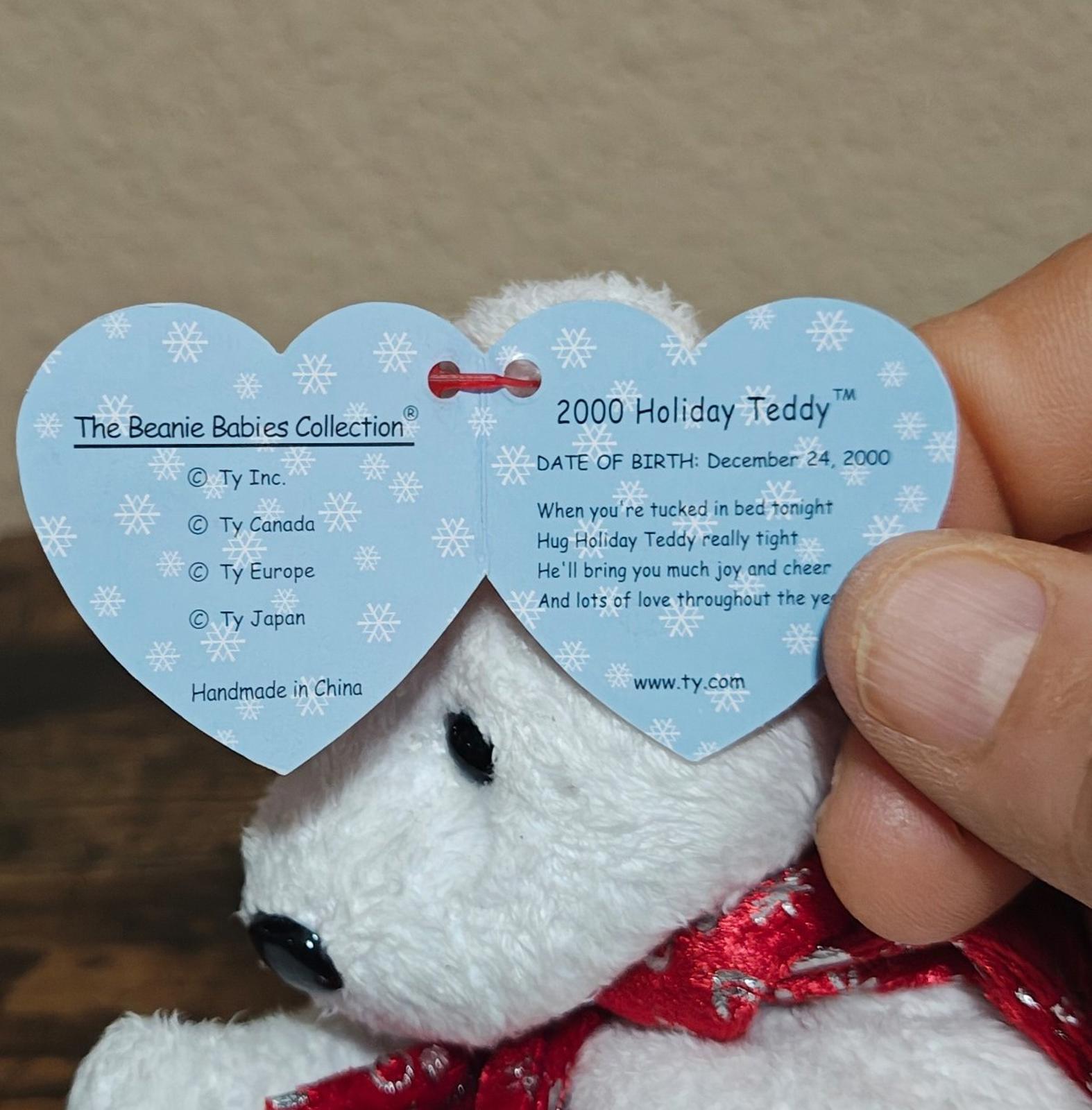 White bear plush with red holiday scarf; heart-shaped tag reads 2000 Holiday Teddy