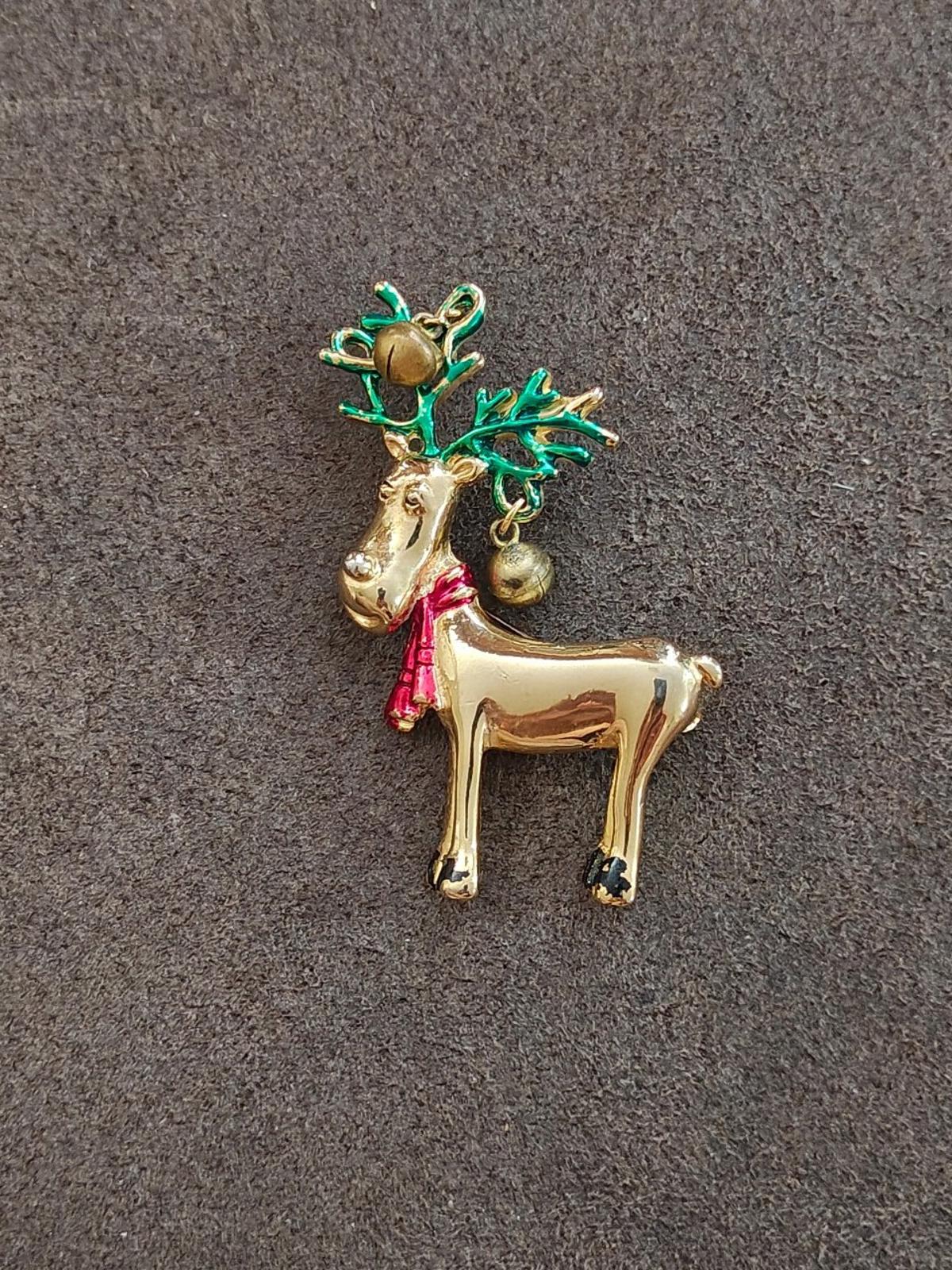 Gold-tone reindeer pin brooch with green antlers, red scarf, and bell details.