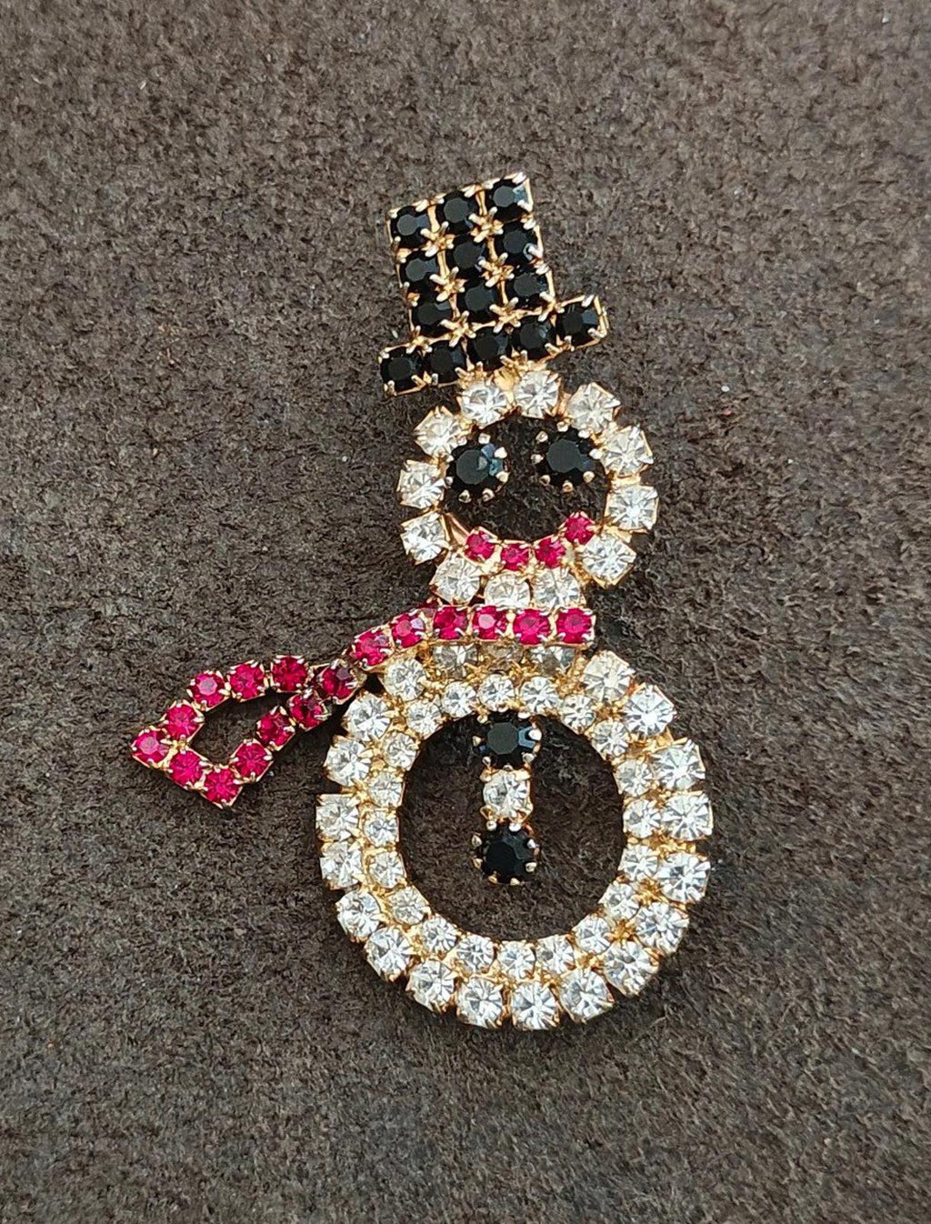 Gold-tone rhinestone snowman brooch with black top, red scarf, and clear stone wreath