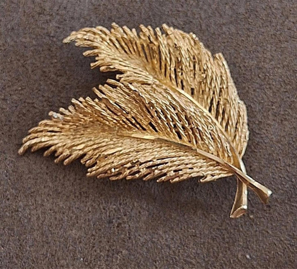 Gold-tone feather leaf brooch with fine textured strands and pin clasp, shown flat