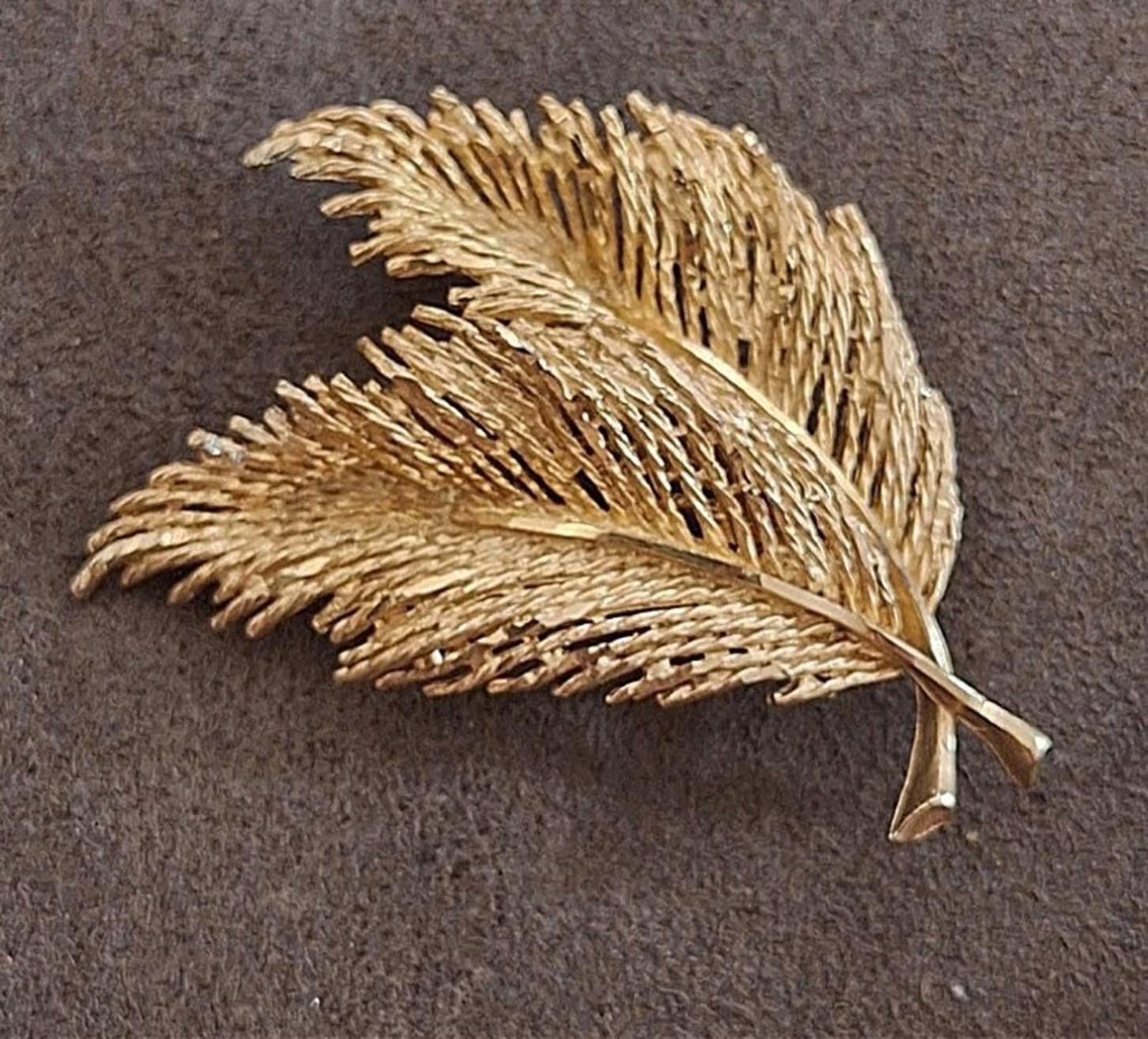 Gold-tone feather leaf brooch with fine textured strands and pin clasp, shown flat