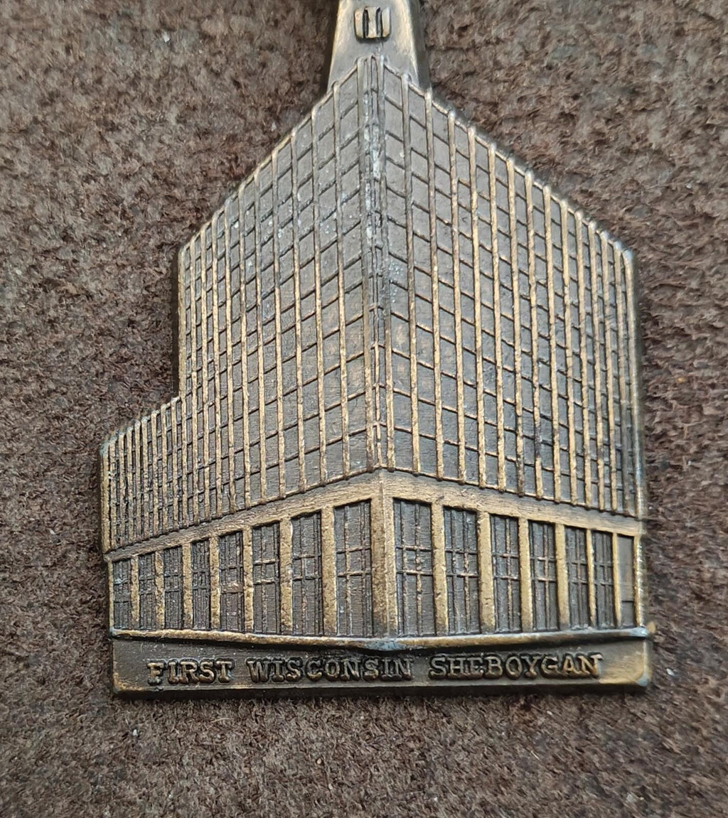 Brass building keychain charm showing side view and engraved bottom text