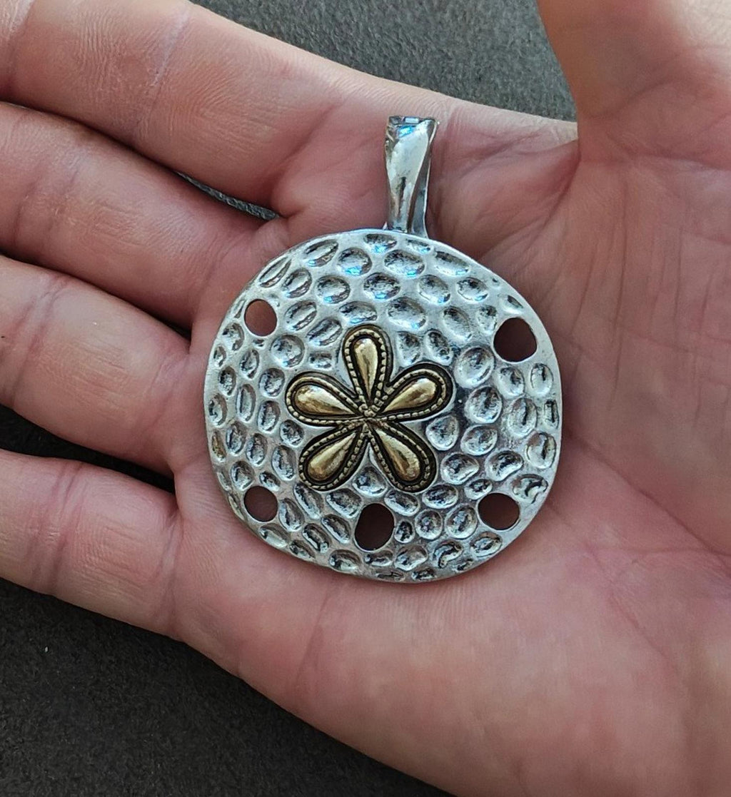 Silver round pendant featuring textured dots and a five-petal two-tone flower design