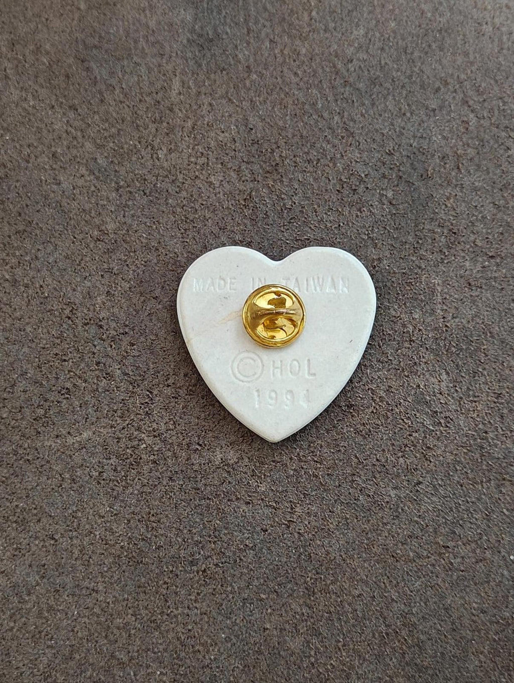 Back of white ceramic heart pin with gold clasp and “MADE IN TAIWAN,” 1994.