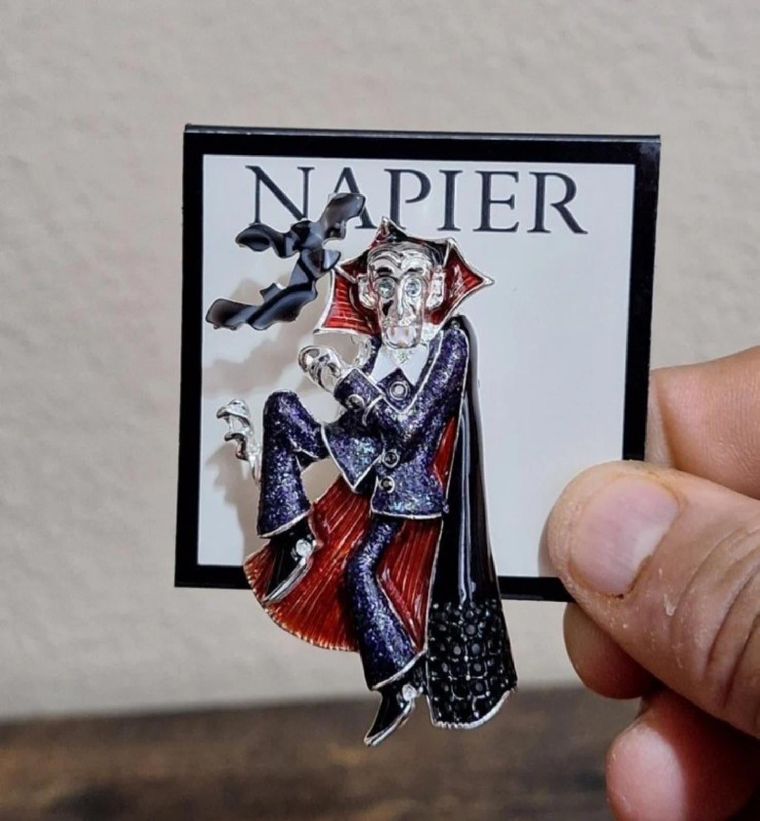 Vampire enamel pin on backing card, red-and-black cape with blue glitter texture