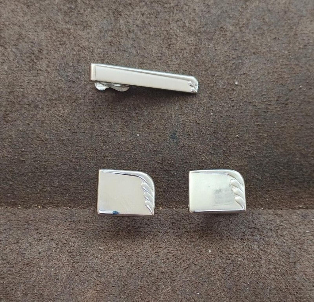 Silver tie bar with rounded ends and two rectangular cufflinks with decorative edge